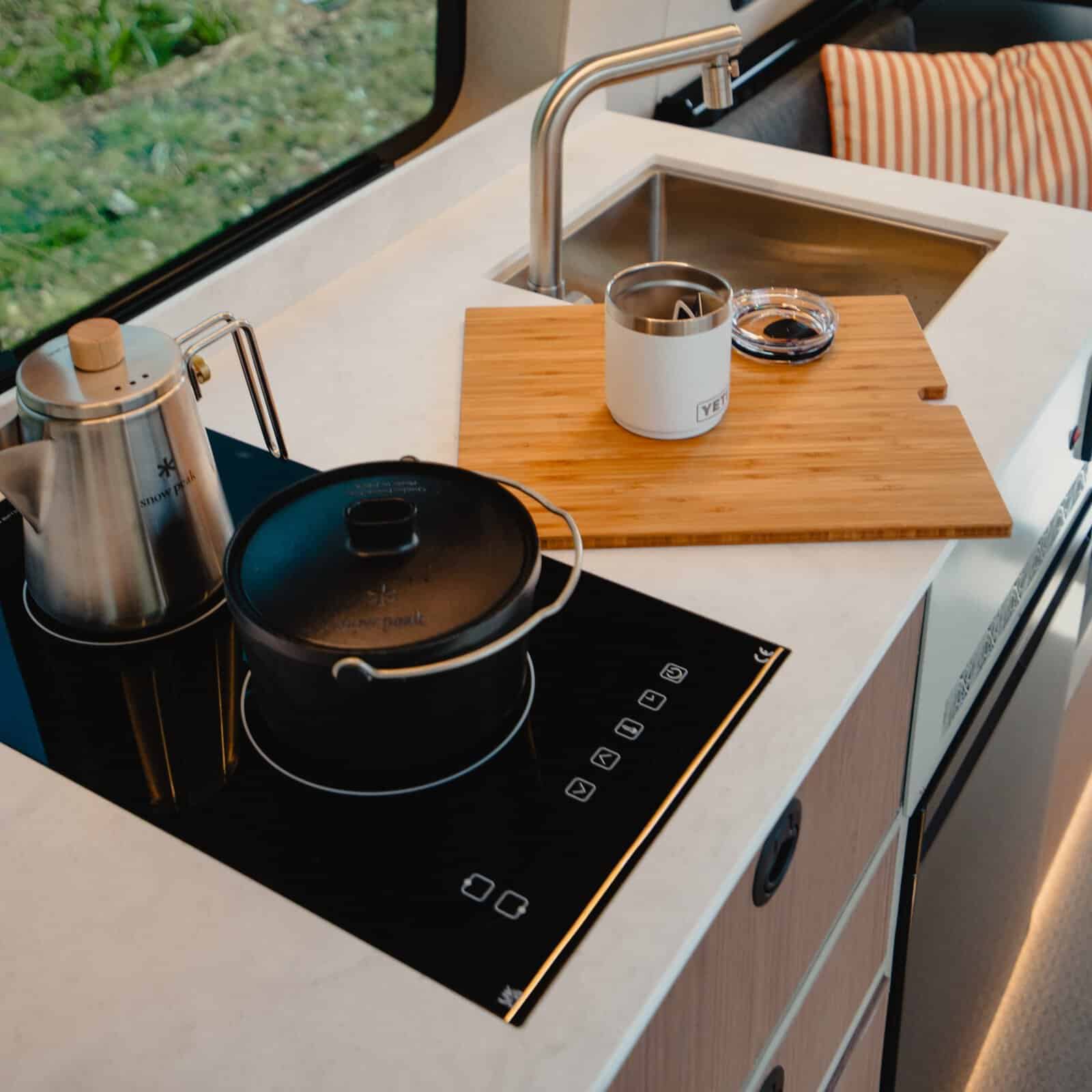 Double-induction kitchen and L-shaped sofa inside the Onyx Summit campervan