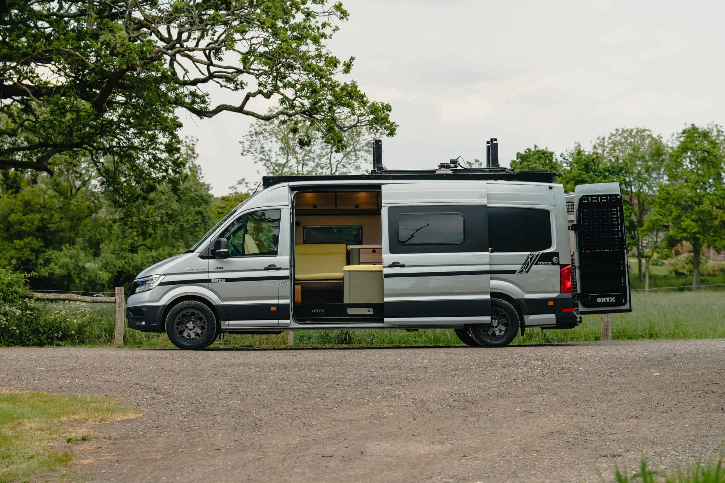 HC 002 — bespoke Onyx Hors Catégorie MAN TGE campervan, side view with sliding door open and roof rack