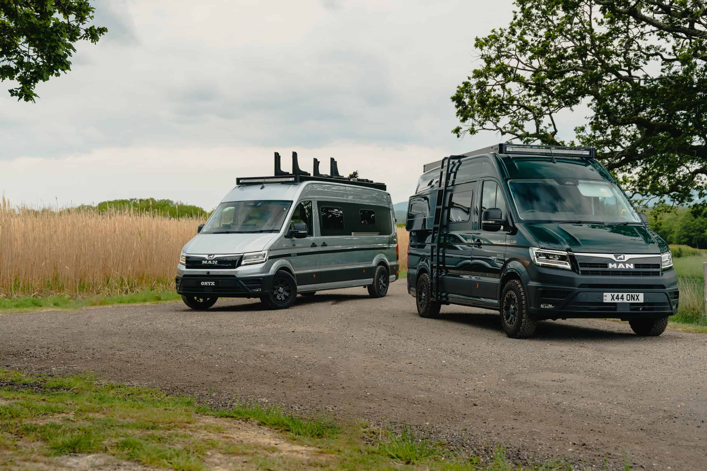 Two bespoke Onyx Hors Catégorie MAN TGE campervans parked by a reed field
