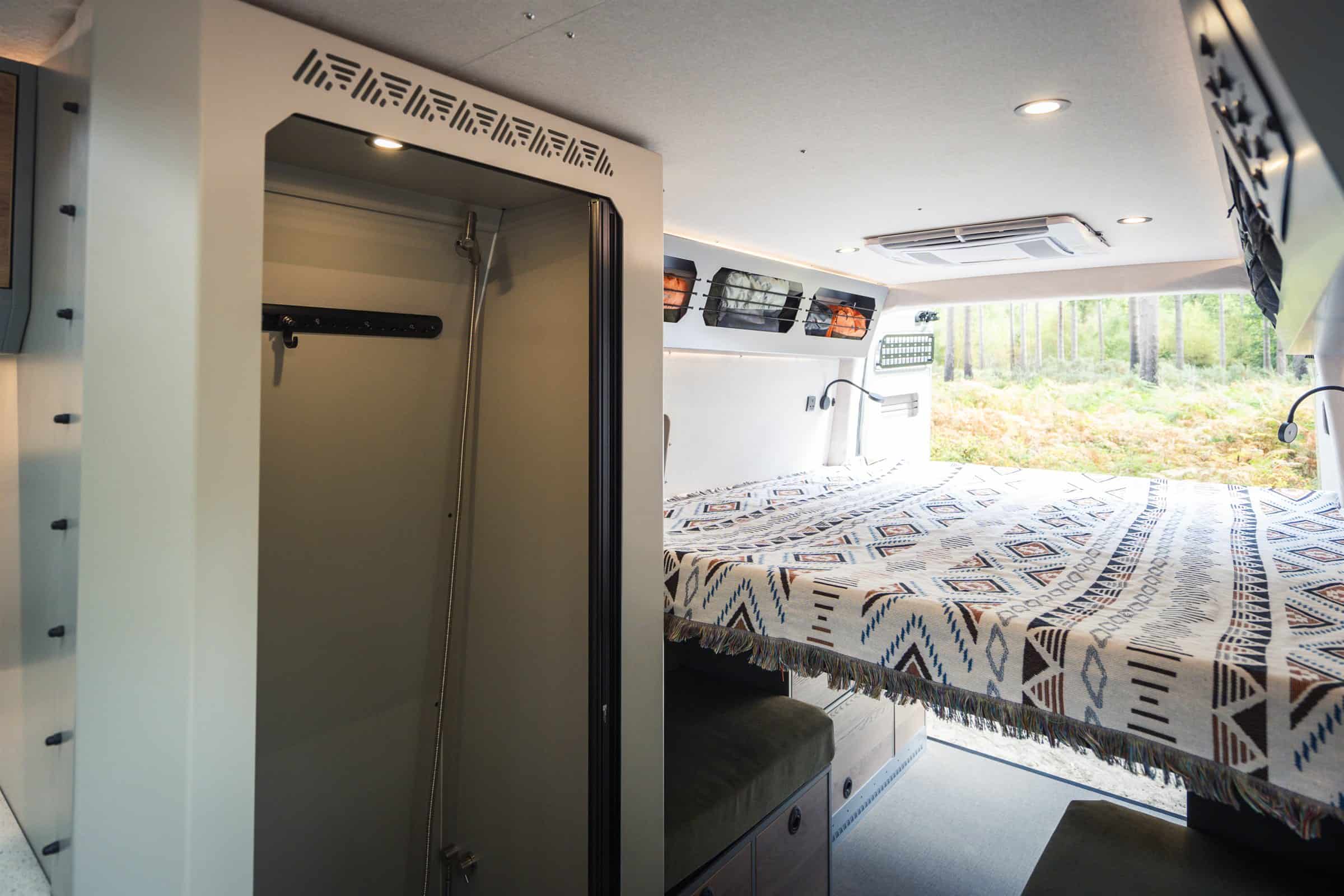 The king-sized lengthways bed in the Onyx Arête, seen past the permanent shower room with the rear doors open