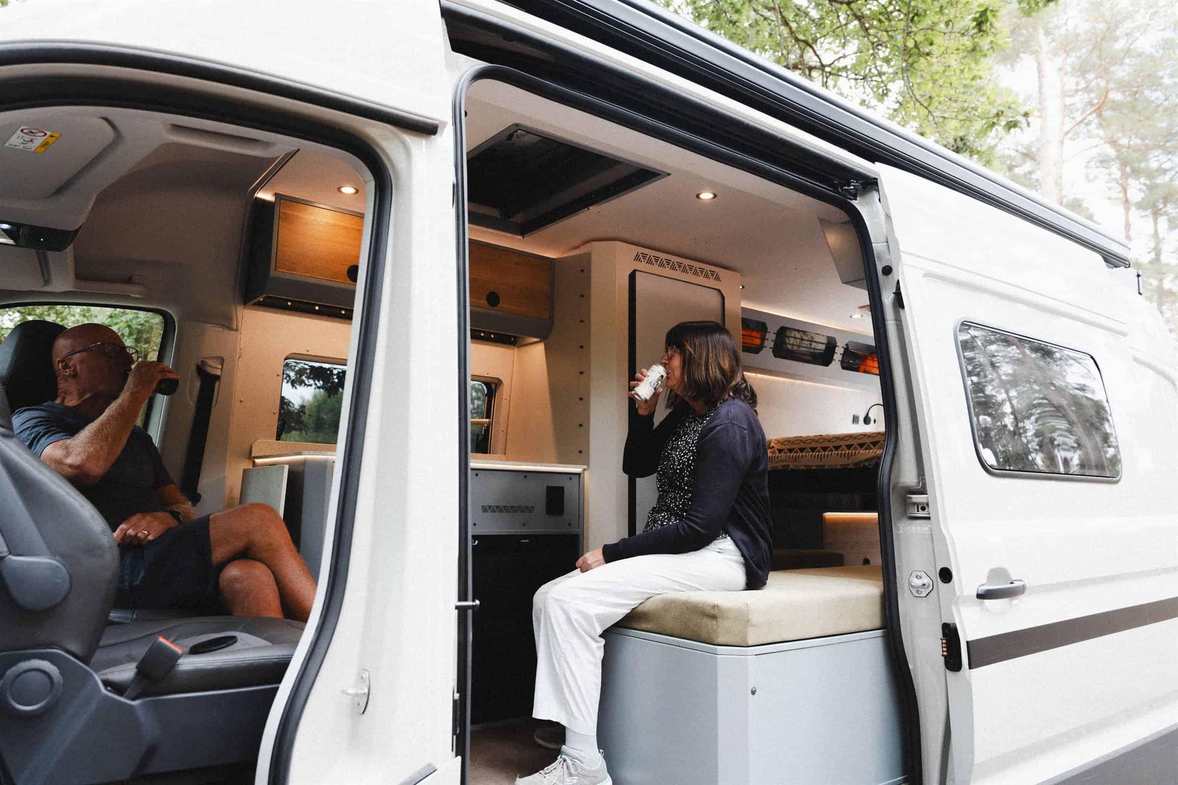 A couple relaxing at the open side door of the Onyx Arête campervan