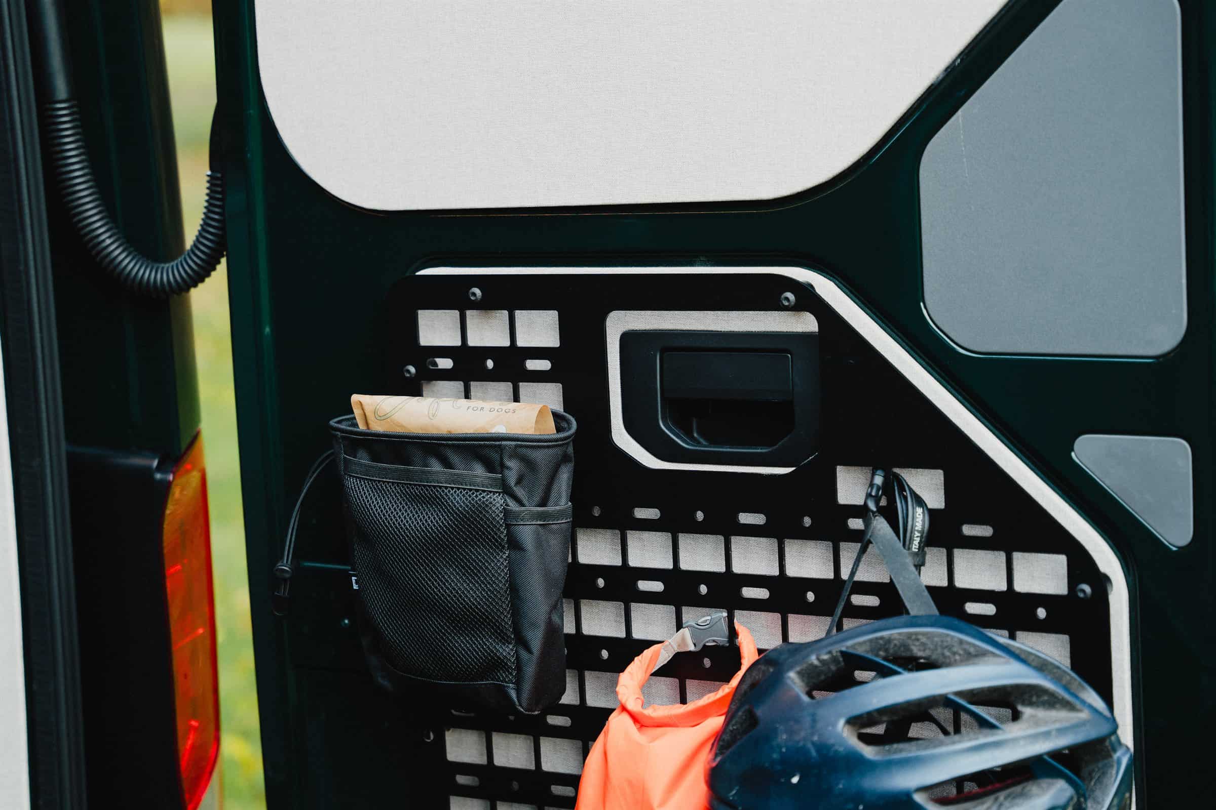 Molle panel on the rear door of an Onyx campervan, with a dry bag and helmet stowed