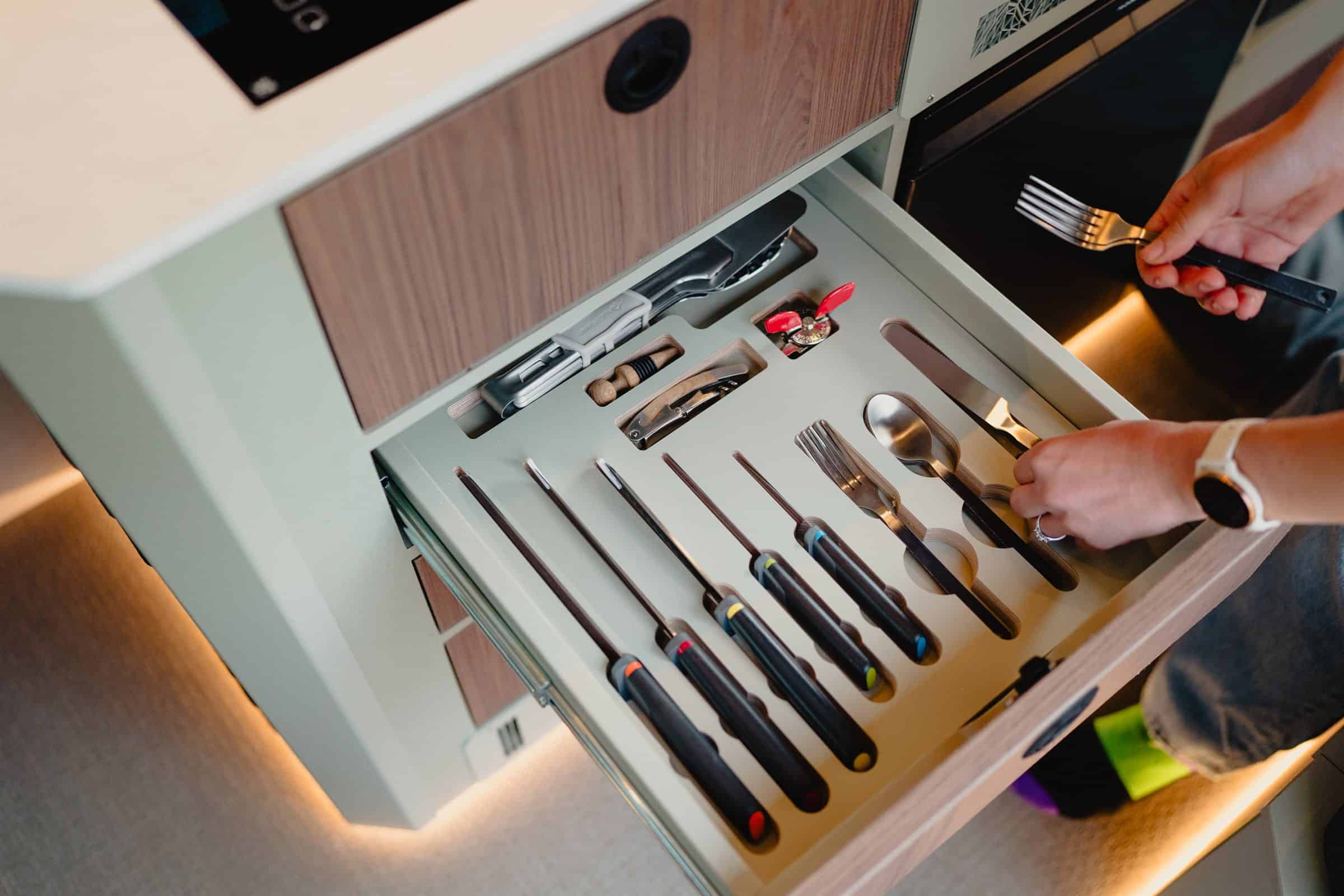 A fitted cutlery and utensil drawer in an Onyx campervan