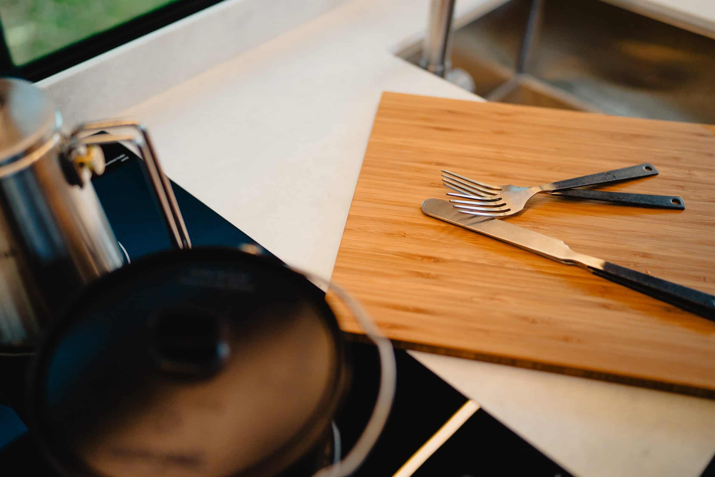 A chopping board, pan and utensils on the worktop of an Onyx campervan