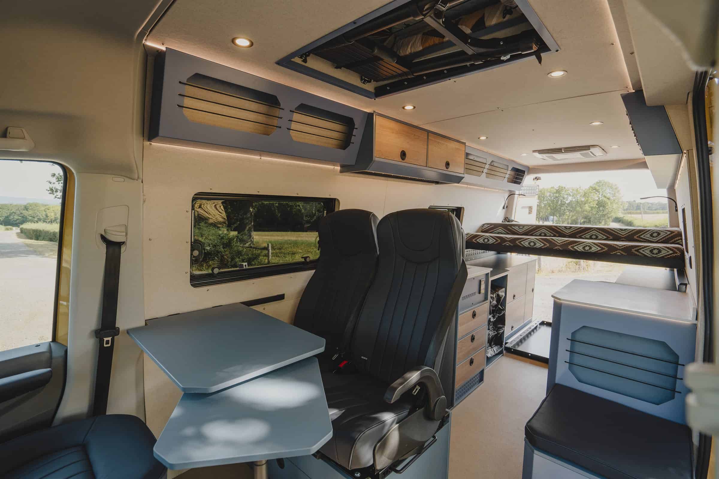 Looking forward through an Onyx campervan to the swivelled cab seat and table, with the bed made up above