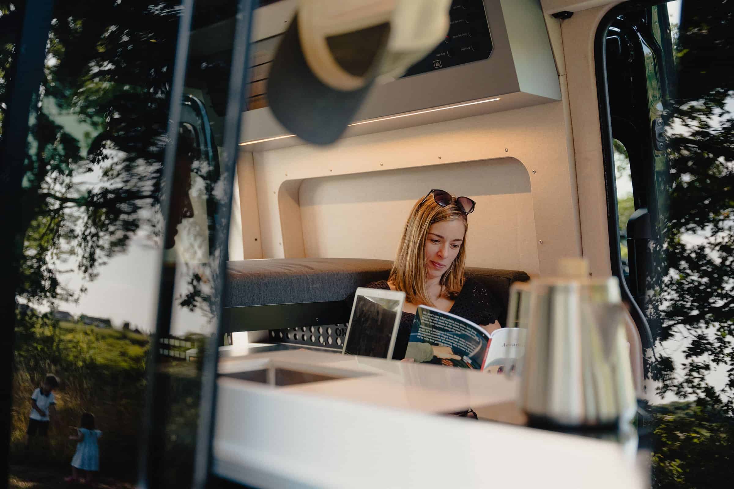 Reading on the bed in the Onyx Summit, with the door open to a field