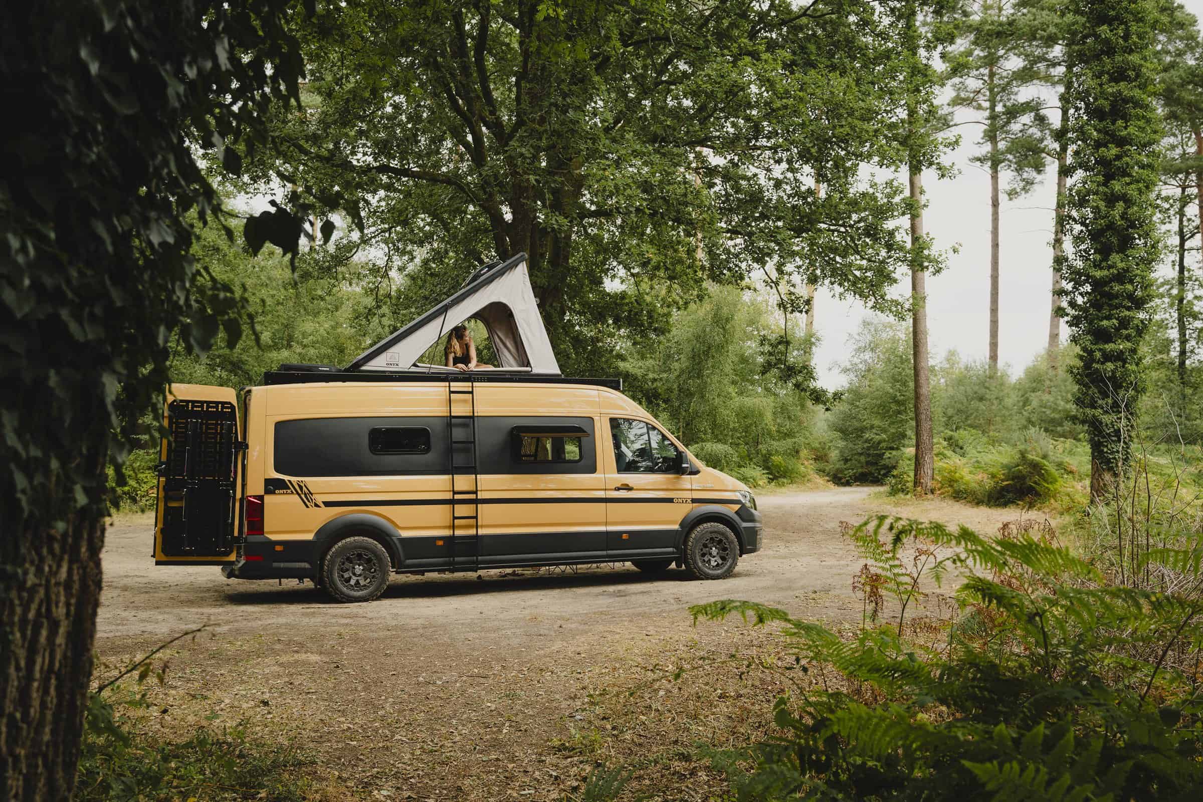 The Onyx Mesa MAN TGE in woodland with the pop-top raised and all-terrain tyres