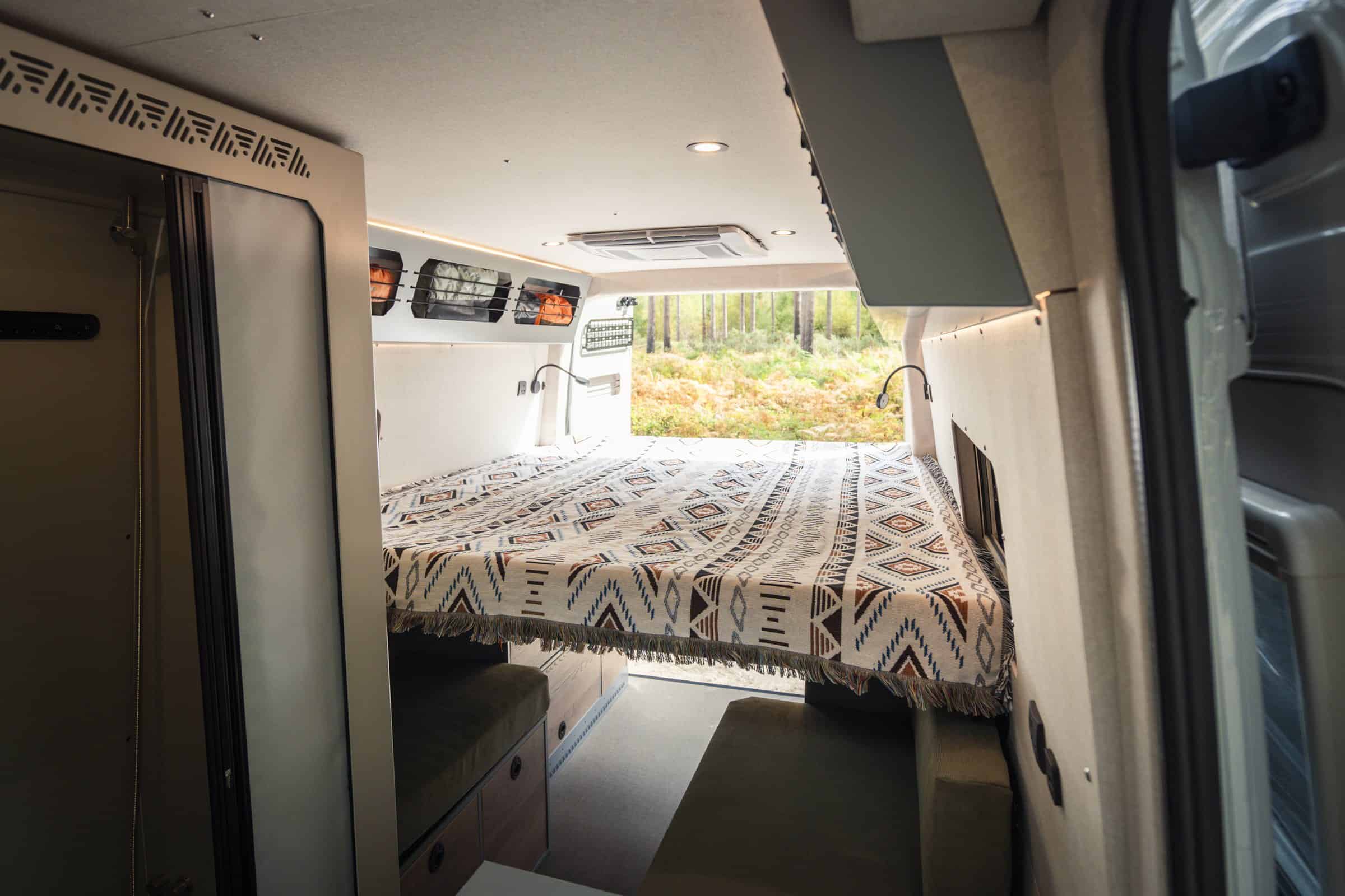 King-sized sliding bed made up in the Onyx Mesa campervan, rear doors open