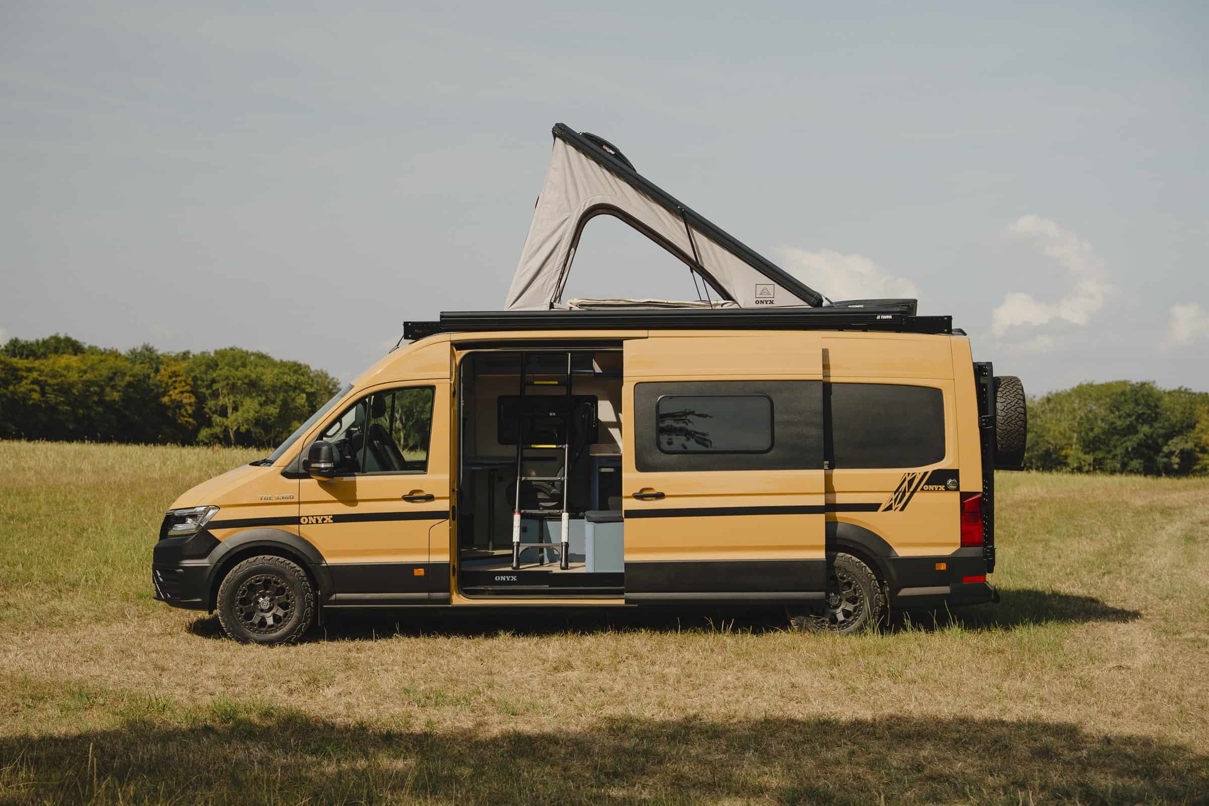 The Onyx Mesa campervan side-on in a field with the pop-top raised and the side door open