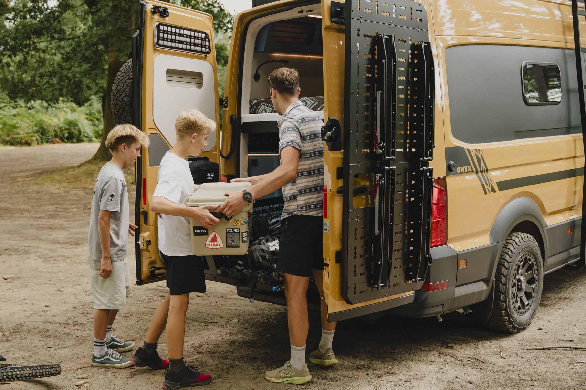 A family loading kit into the rear of the Onyx Outpost campervan