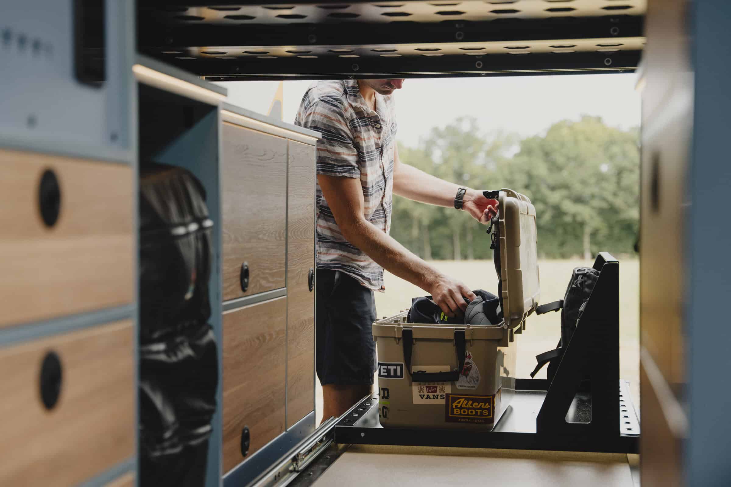 Loading gear into the rear pull-out storage tray of the Onyx Outpost campervan