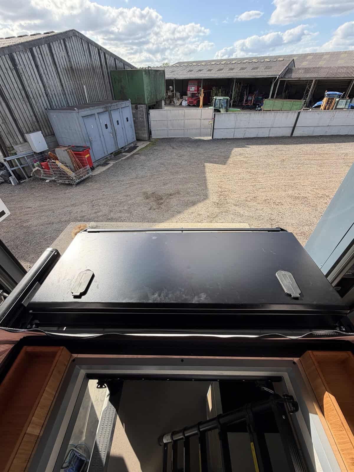 Looking out through the open hatch of an Onyx pop-top to the front storage box on the roof rack, with the ladder below