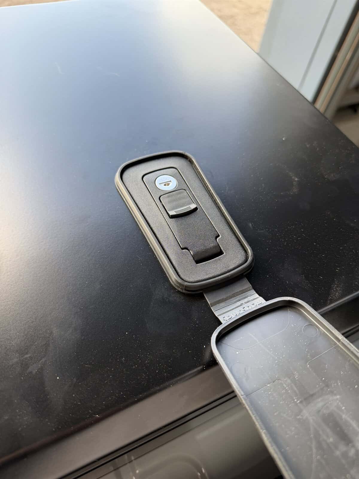 A closed locking catch on the Onyx front storage box, with its weather cover folded back