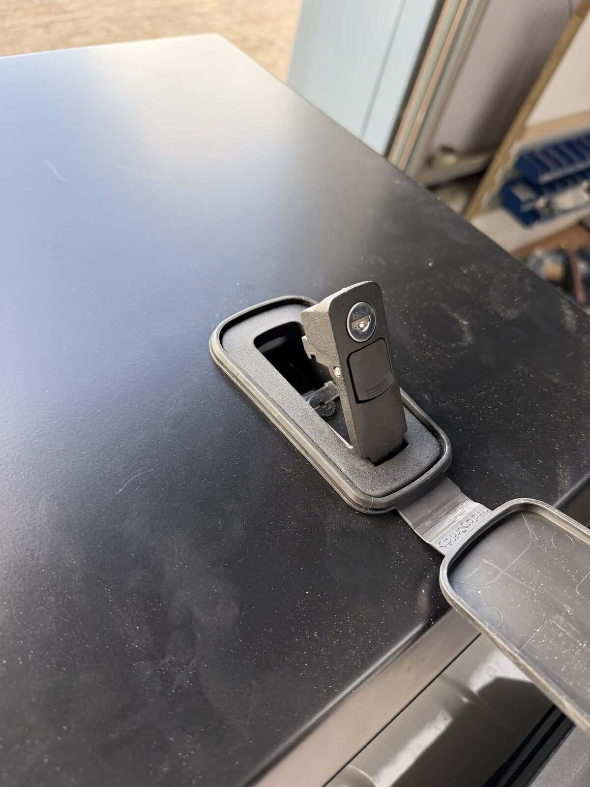 The locking catch on the Onyx front storage box lifted open, showing the key barrel and its weather cover