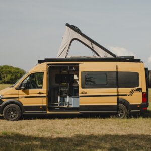 Side profile of a MAN TGE campervan in a field with the Onyx pop-top raised to full height