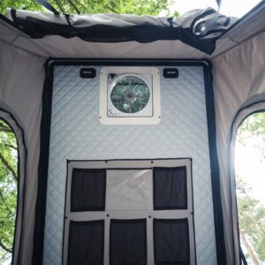 A Maxxair fan fitted into the wall of an Onyx pop-top, with a storage panel below it