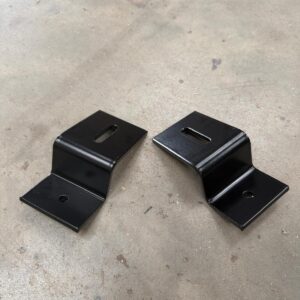 A pair of powder-coated Onyx solar mounting brackets on the workshop floor
