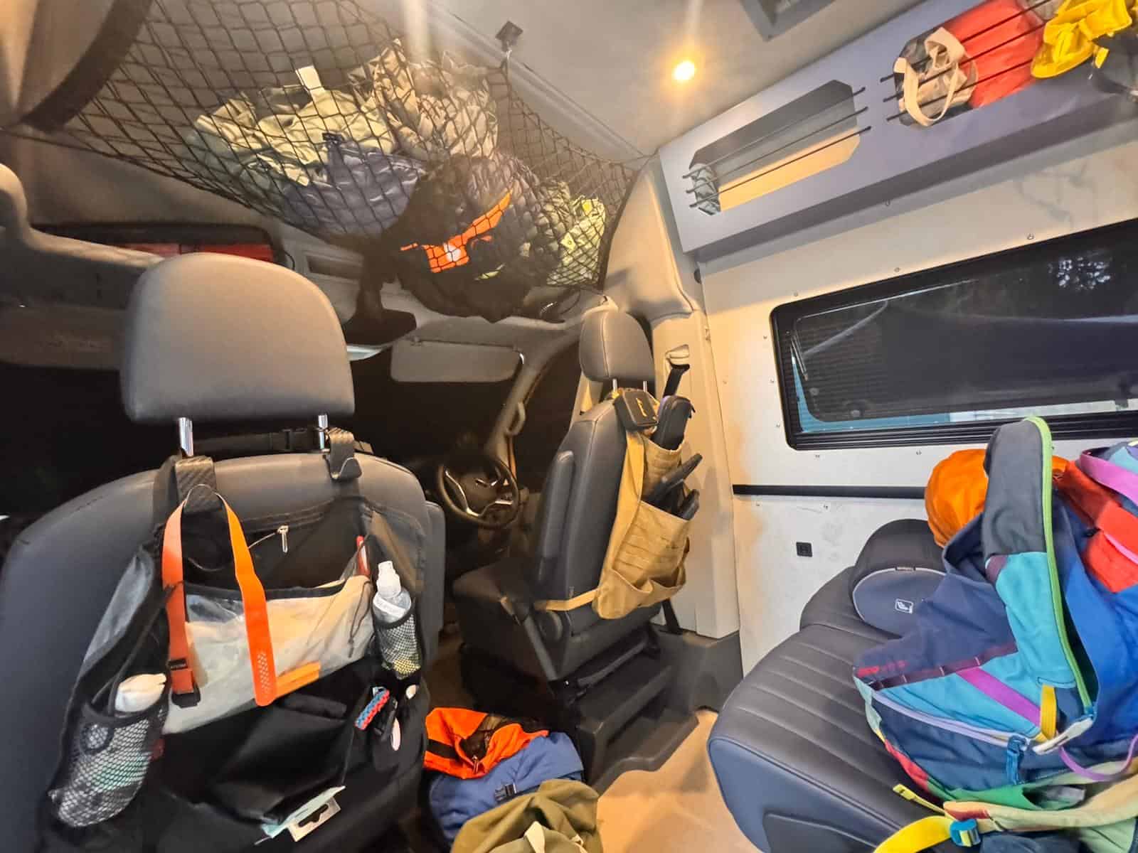 The cab seen from the back of the van, seat-back organisers full of kit and a cargo net overhead
