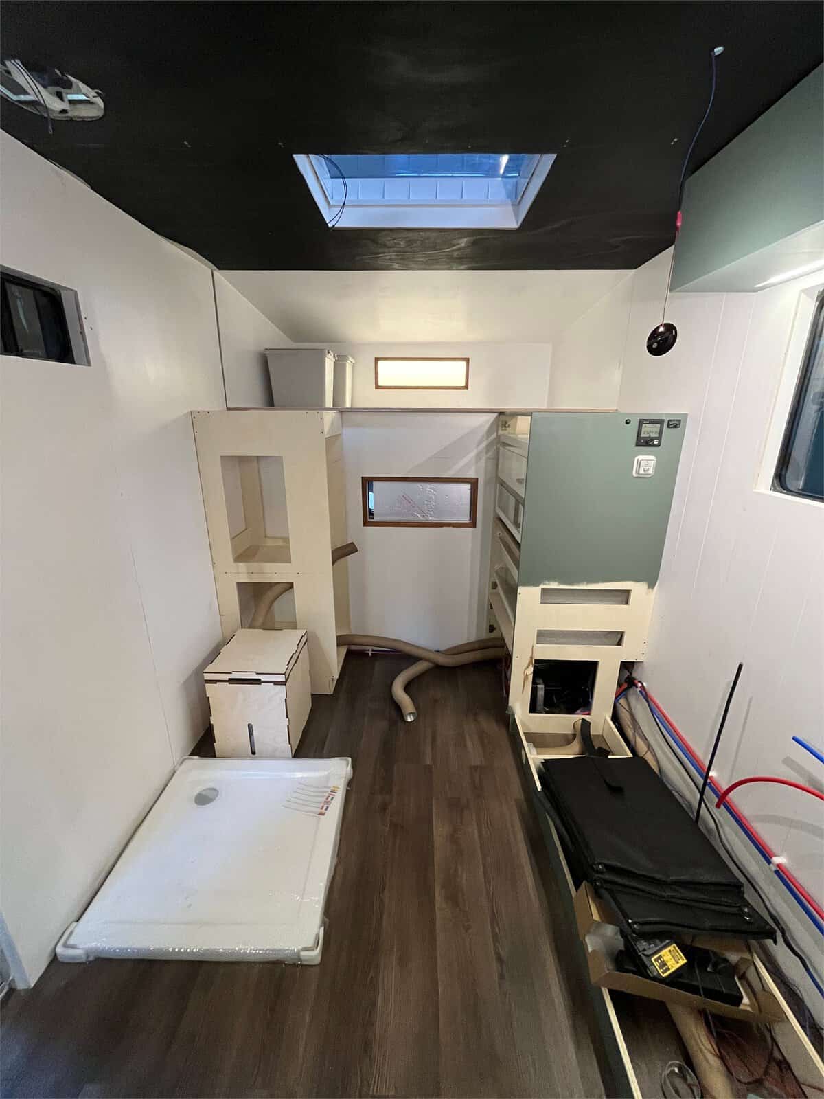 Luton van conversion mid-build, with the shower tray, units and wiring in place