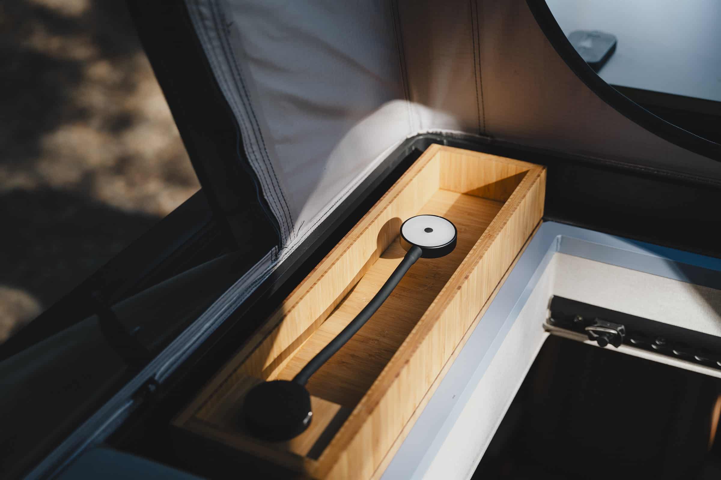 A bamboo storage box inside the Onyx pop-top with its reading light folded flat inside