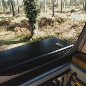 The Onyx front storage box closed on the roof rack, seen from inside the pop-top, with a bamboo storage box beside the berth