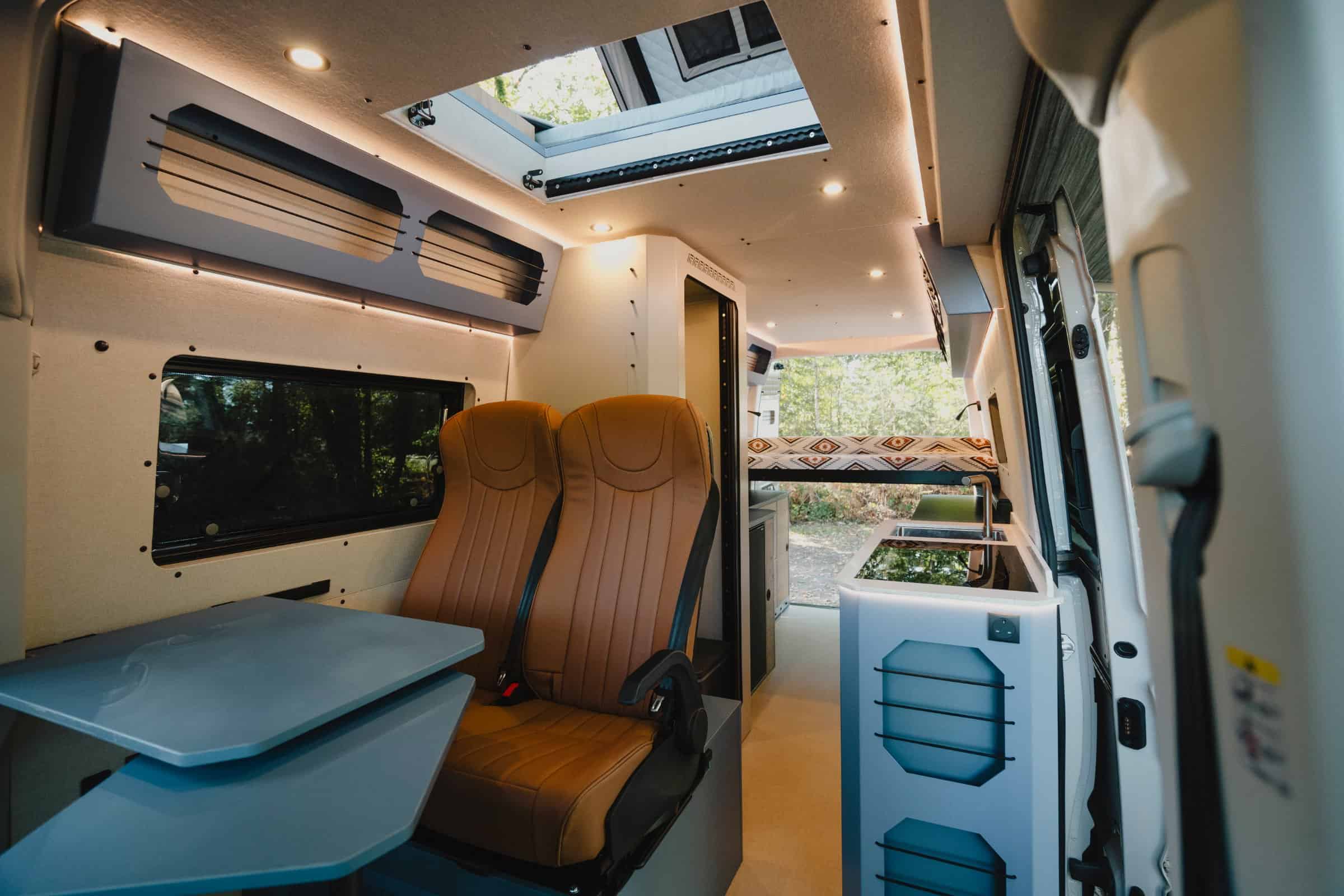 The whole interior of the Onyx Mesa from the side door: travelling seats, table, kitchen, skylight and the bed beyond